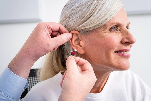 Eine ältere Frau erhält ein modernes Hörgerät zur Verbesserung ihres Hörvermögens.